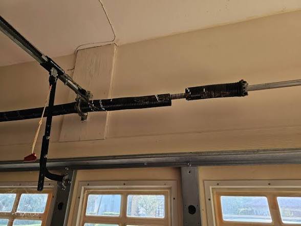 Technician installing a new garage door torsion spring